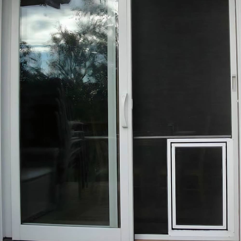 The Security Boss Screen Pet Door Designed for Sliding Screen Doors is fully visible, closed at the bottom of a sliding screen door with a black mesh securely framed in white