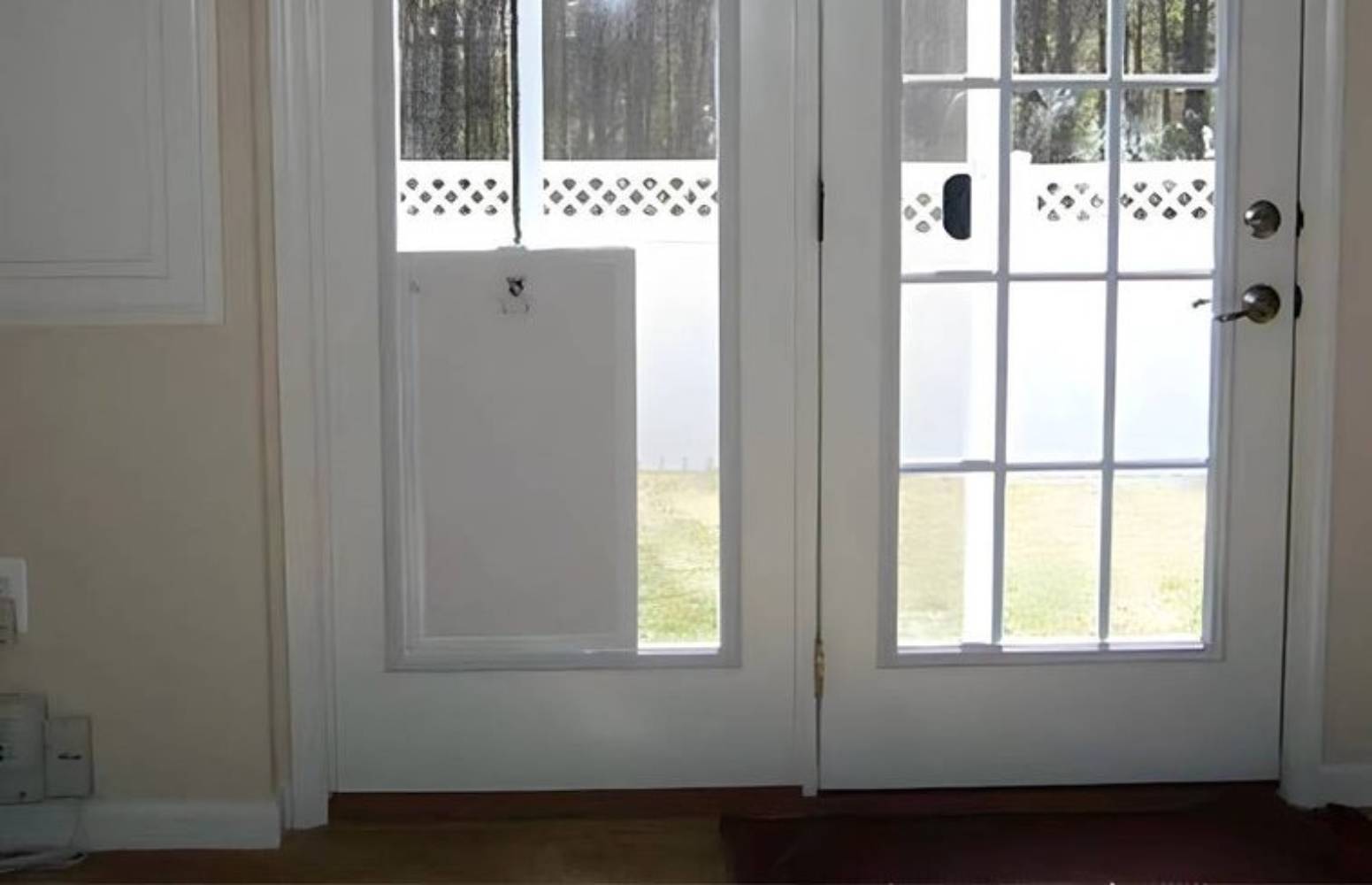 A close-up photo of a white automatic dog door installed in a sliding glass door for what are the best automatic dog doors