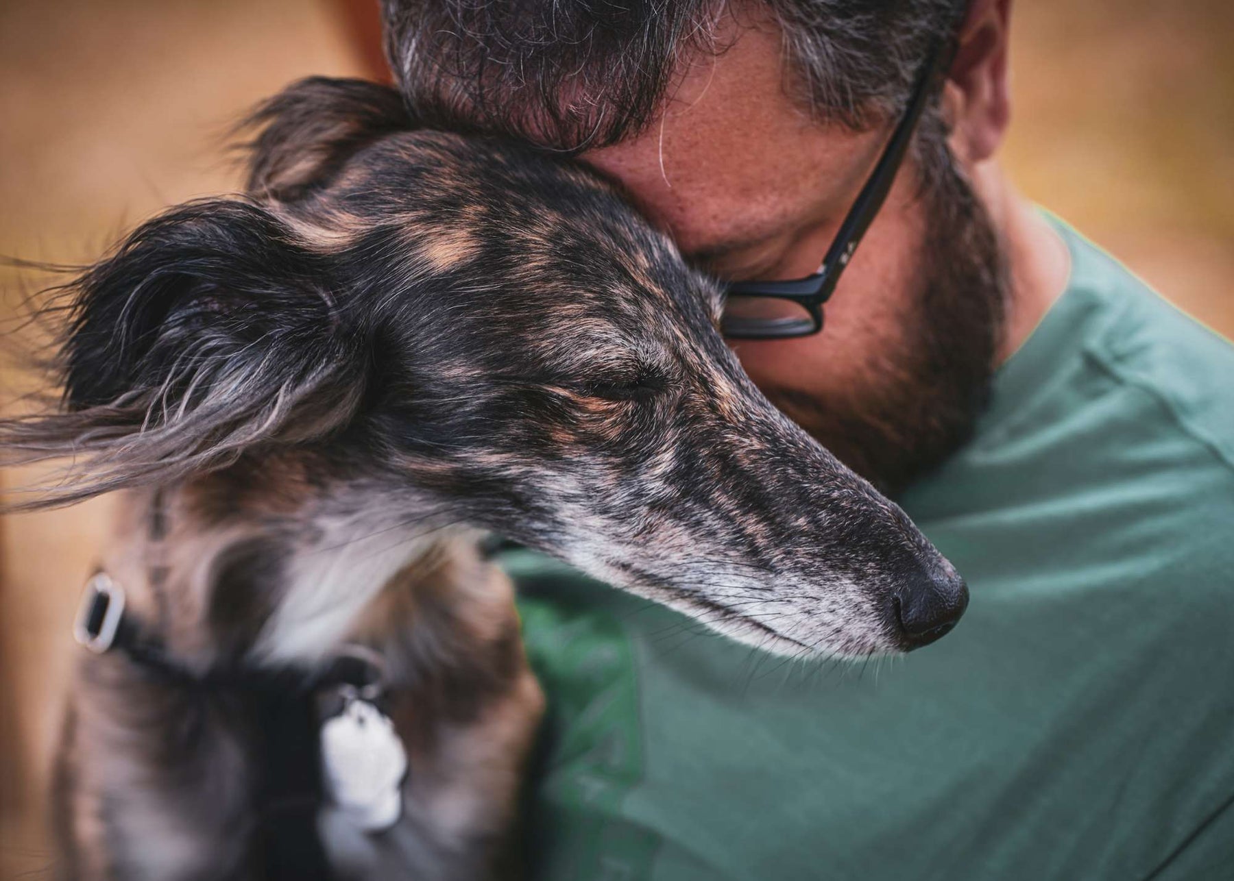 A man presses his forehead to his dog’s head as they rest together with closed eyes, capturing the quiet pain and love in how to heal after saying goodbye to your dog