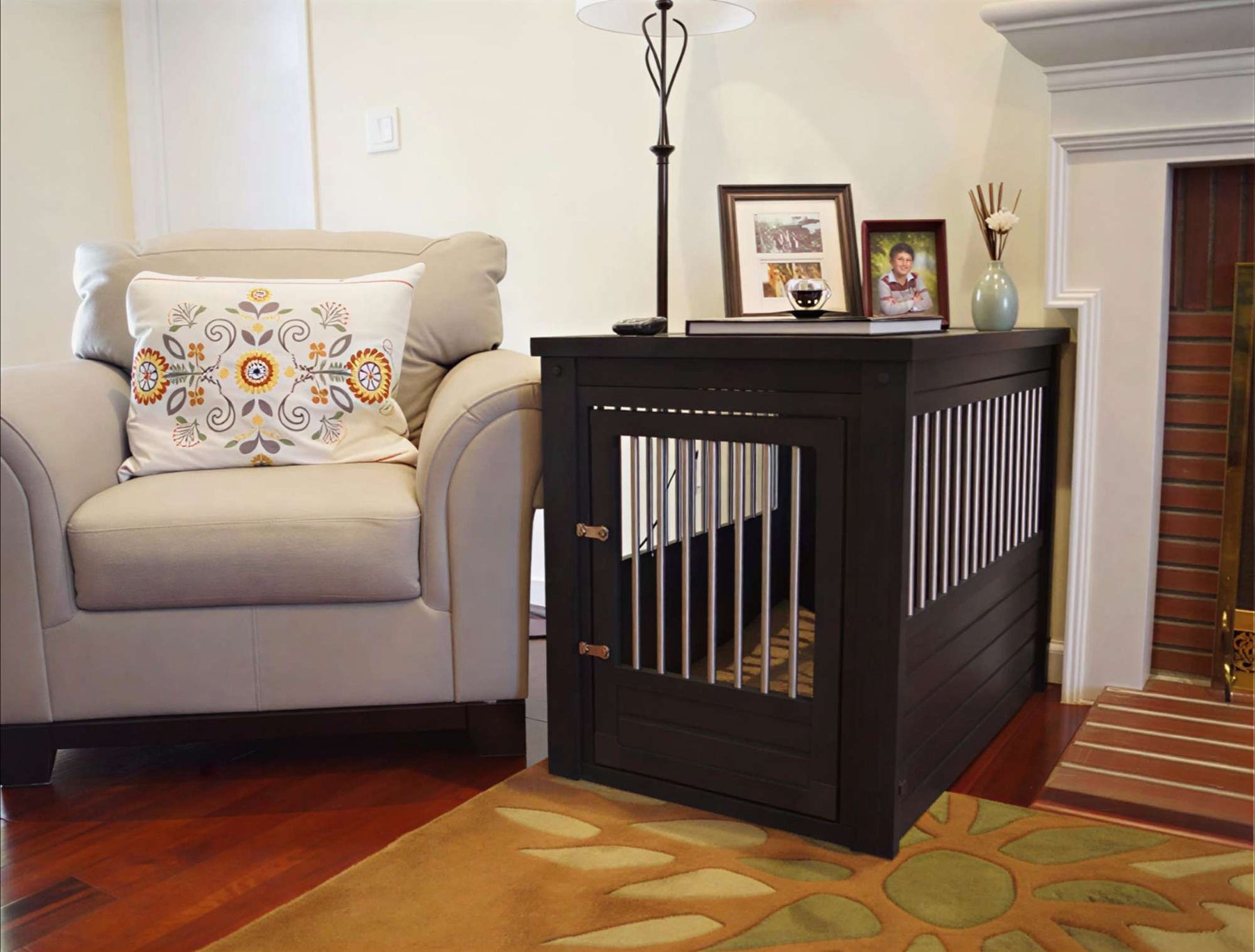Dark wood decorative dog crate with metal bars styled as a side table beside a beige armchair in a cozy living room
