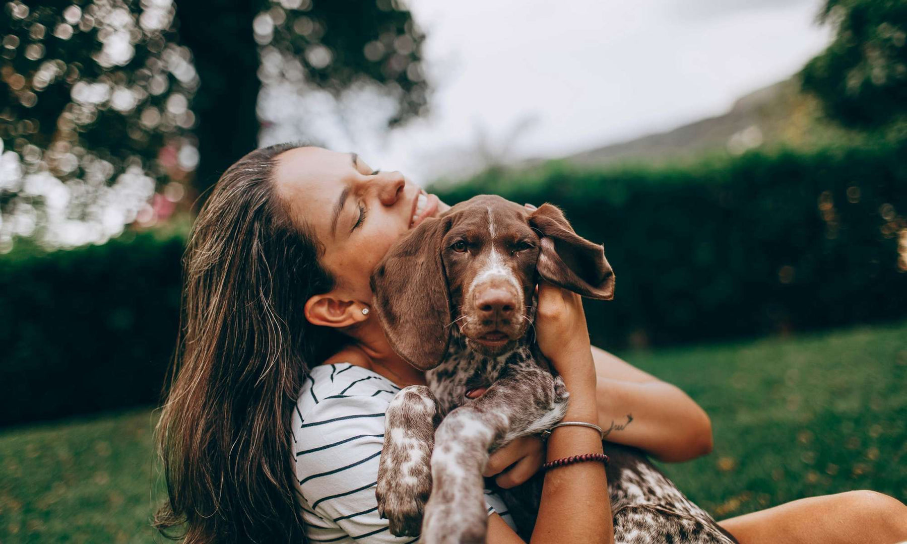 Woman hugs a relaxed dog outdoors, showing warmth and companionship that reflect how dogs make us better humans
