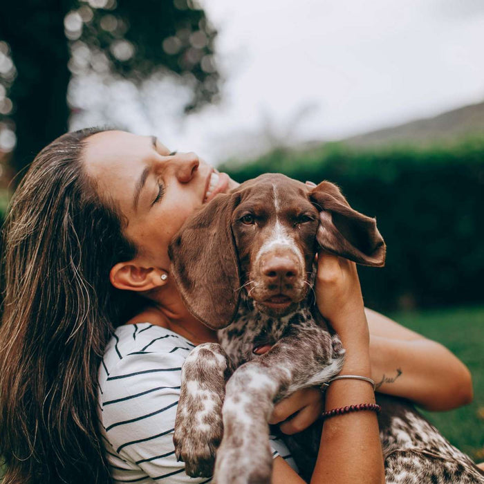 Woman hugs a relaxed dog outdoors, showing warmth and companionship that reflect how dogs make us better humans