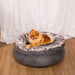 A Pomeranian enjoys the comfort of the Ultra Soft Chinchilla Paw PupPouf™ Luxe Faux Fur Donut Dog Bed with a happy expression