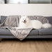 A Samoyed is lying on a bed covered with the Paw PupProtector™ Waterproof Throw Blanket - Ultra Soft Chinchilla