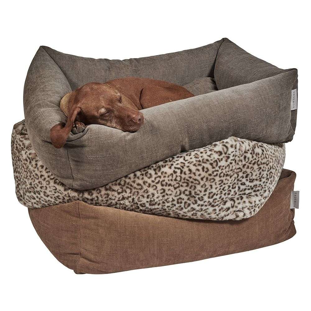 A brown dog naps in a gray fabric Bowsers The Franklin Dog Bed, stacked on top of two others in leopard print and brown