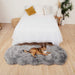 A brown and white dog lounging on a Paw PupRug™ Runner Faux Fur Memory Foam Dog Bed Charcoal Grey at the foot of a white bed in a minimalist bedroom