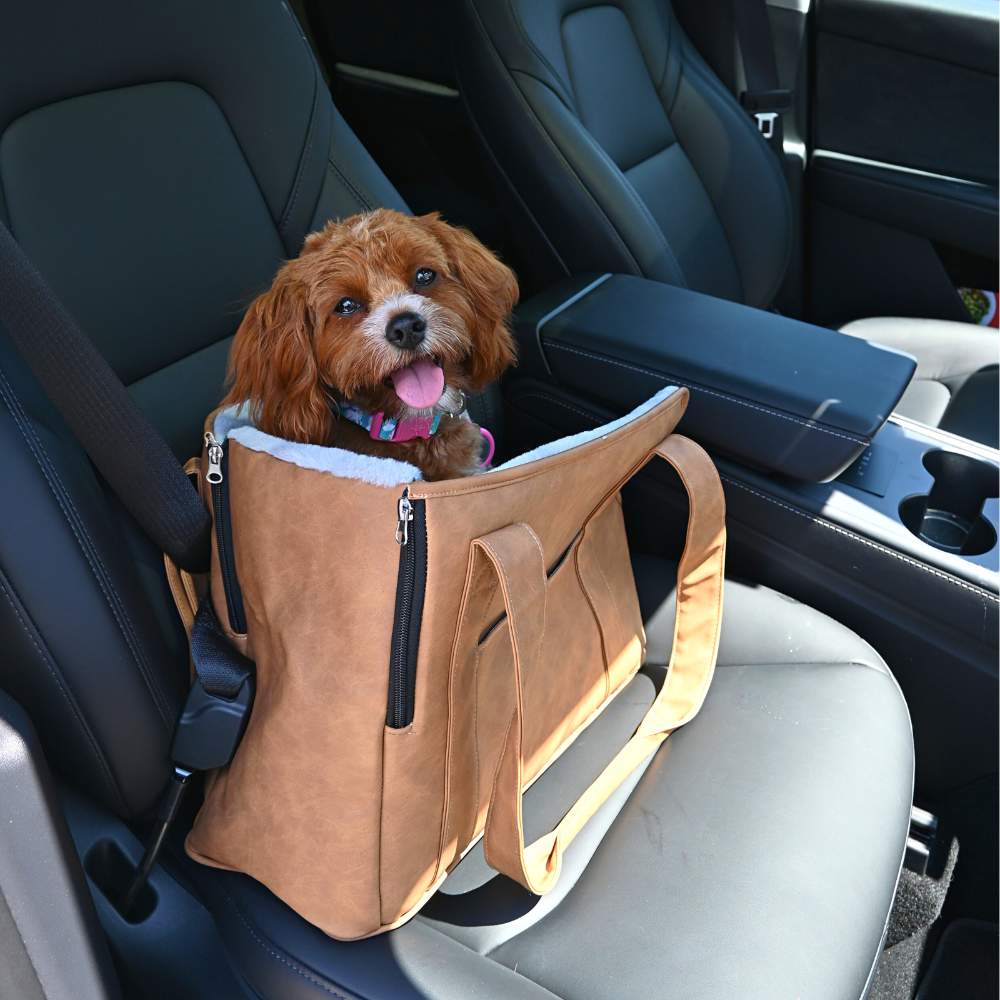 A cheerful brown dog in a car seat inside the Paw PupTote™ 3-in-1 Faux Leather Dog Carrier Bag - Camel with the car interior visible