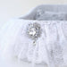 A close-up of the decorative brooch on the Hello Doggie Crib Dog Bed in grey, showcasing intricate lace ruffles and sparkling crystal embellishments