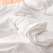 A close-up of white bedding with a crumpled look, emphasizing the Paw PupSheets™ Hair Resistant, Antimicrobial, & Cooling Duvet Cover and Sheet Set Bundle - White