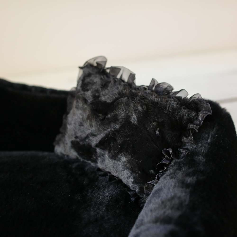 A close-up view of a luxurious black pillow with delicate ruffles, part of the Hello Doggie Divine Dog Bed collection