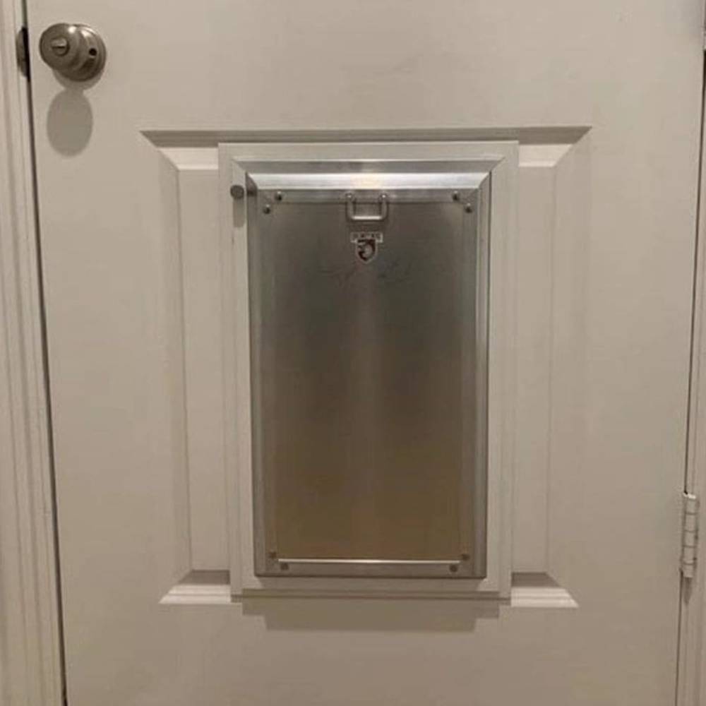 A close-up view of the Security Boss MaxSeal PRO High-Grade Aluminum Dog Door installed on a white door