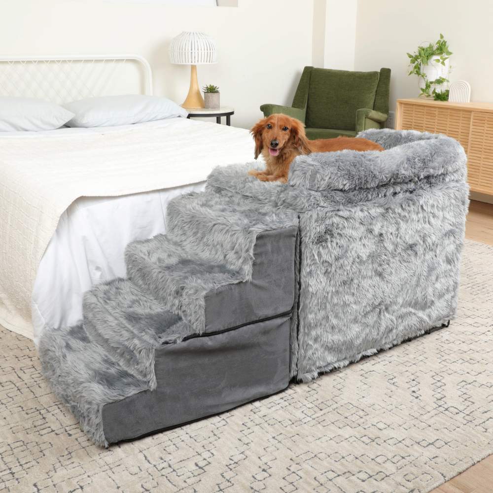 A dog is comfortably lying on the Paw Pet Bedside Sleeper Crate Kit & Stairs next to a bed