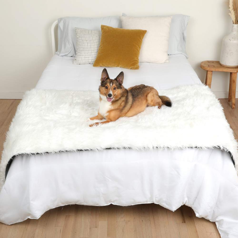 A dog is comfortably resting on a bed with the Paw PupProtector™ Waterproof Bed Runner - Polar White Pet Blanket
