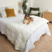 A dog is lounging on a bed with the Paw PupProtector™ Waterproof Bed Runner - Polar White Soft Dog Blankets