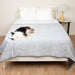 A dog is lying on a bed covered with the Paw PupChill™ Cooling Waterproof Blanket - Arctic Grey Dog Blanket