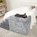 A dog is sleeping on the Paw Pet Bedside Sleeper Dog Crate Kit & Pet Stairs beside a bed where a woman is also sleeping