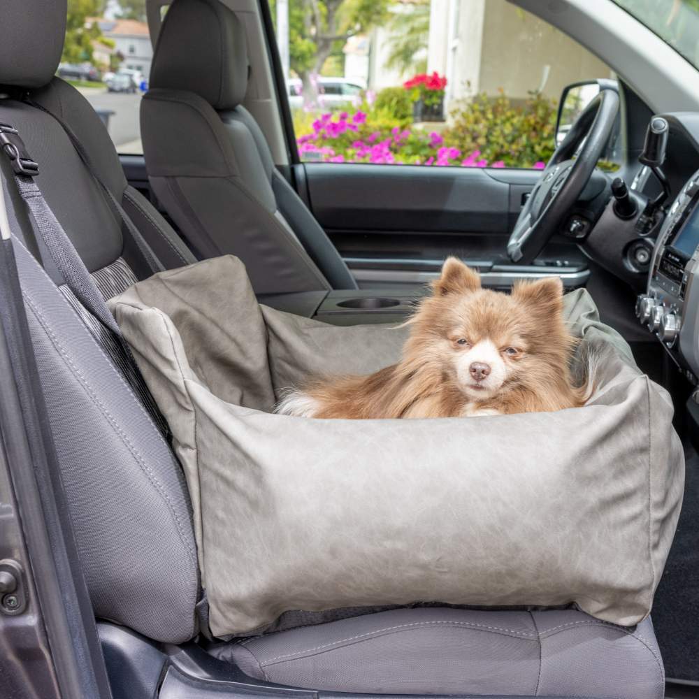 A fluffy dog is comfortably sitting in the front passenger seat in the Paw PupProtector™ Faux Leather Memory Foam Dog Car Bed - Slate Gray