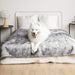 A fluffy white dog lounges comfortably on a bed covered with the Paw PupProtector™ Waterproof Throw Blanket - Ultra Plush Arctic Fox
