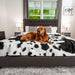 A golden retriever is lying on a bed with the Paw PupProtector™ Waterproof Throw Blanket - Black Faux Cowhide Waterproof Dog Blanket