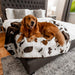 A golden retriever is lying on a bed with the Paw PupProtector™ Waterproof Throw Blanket - Brown Faux Cowhide Dog Blanket