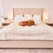 A golden retriever is resting on a bed covered with the Paw PupProtector™ Short Fur Waterproof Throw Blanket - Polar White in a bright bedroom