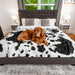 A golden retriever is resting on a bed covered with the Paw PupProtector™ Waterproof Throw Blanket - Black Faux Cowhide Waterproof Dog Blankets