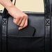 A hand placing a phone into the exterior pocket of the Paw PupTote™ 3-in-1 Faux Leather Dog Carrier Bag - Black