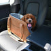 A happy brown dog sitting comfortably in a car seat inside the Paw PupTote™ 3-in-1 Faux Leather Dog Carrier Bag - Camel