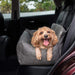 A happy dog is resting in the Paw PupProtector™ Faux Leather Memory Foam Dog Car Bed - Slate Gray, placed in the back seat of a car