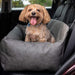 A happy dog is sitting in the Paw PupProtector™ Faux Leather Memory Foam Dog Car Bed - Slate Gray Double Seat Pet Bed, placed in a car seat