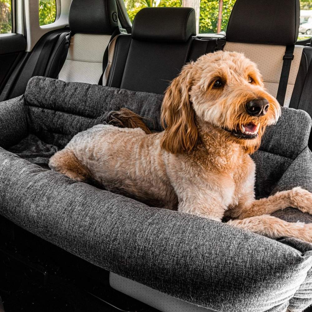 A large brown dog is laying relaxed in the back seat of a car on a Paw PupProtector™ Memory Foam Dog Car Bed