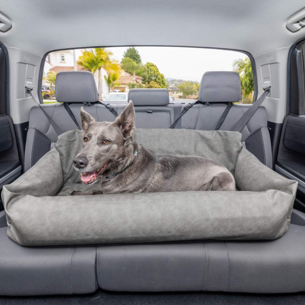 A large dog is comfortably resting in the back seat in the Paw PupProtector™ Faux Leather Memory Foam Dog Car Bed - Slate Gray Full Back Seat Car Dog Bed