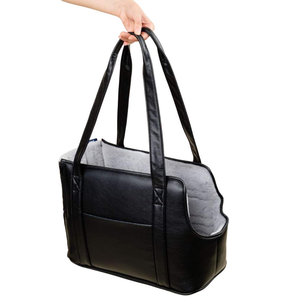 An empty Paw PupTote™ 3-in-1 Faux Leather Dog Carrier Bag - Black being held by its handles
