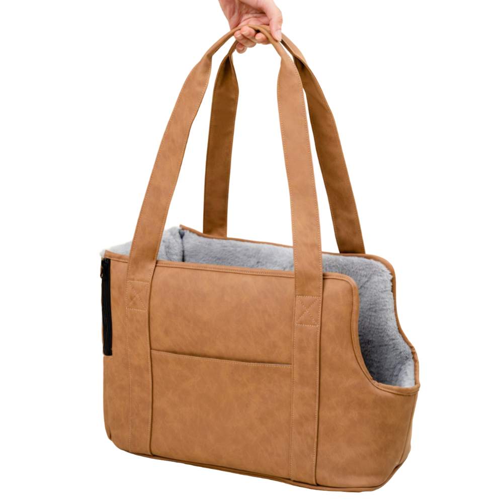 An empty Paw PupTote™ 3-in-1 Faux Leather Dog Carrier Bag - Camel being held by its handles, displaying its structure and design