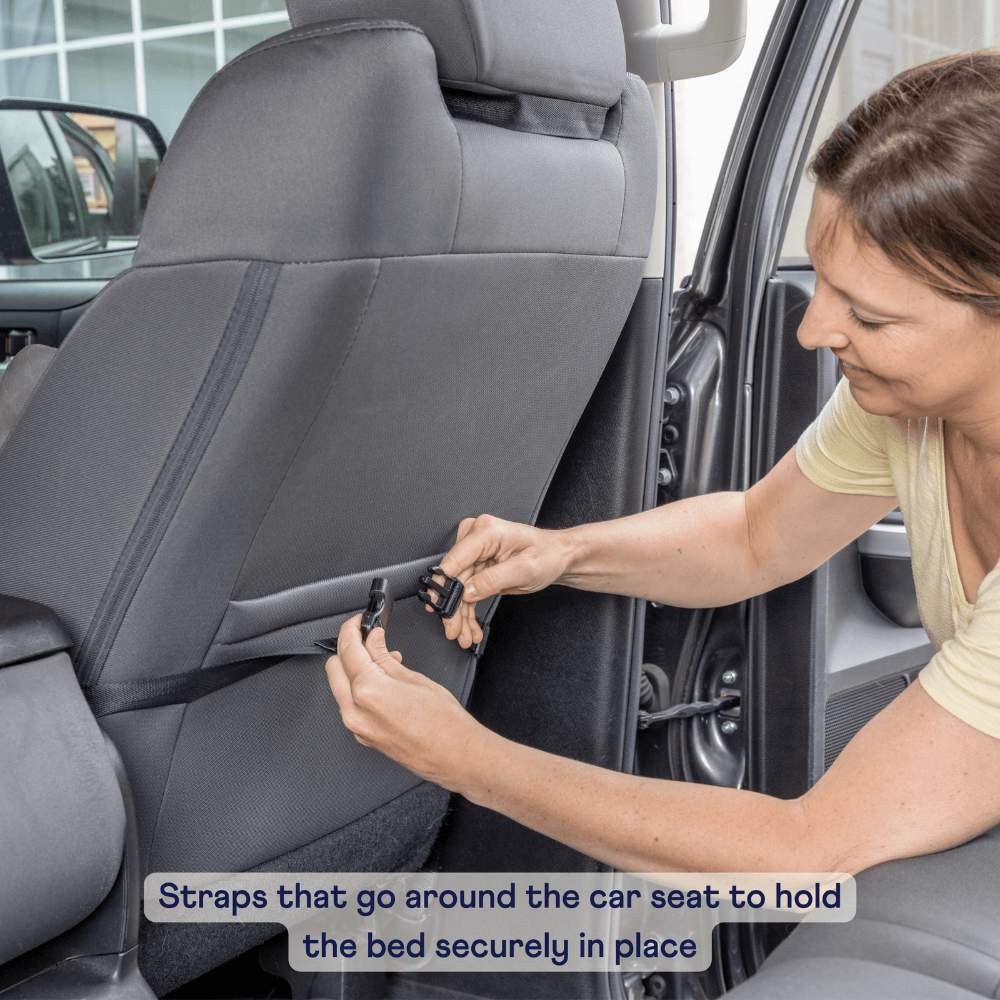 A person is securing the straps around a car seat to hold the Paw PupProtector™ Memory Foam Dog Car Bed in place