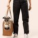 A pug being carried by a person in the Paw PupTote™ 3-in-1 Faux Leather Dog Carrier Bag - Camel, with the person's lower body and feet visible