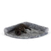 A small black dog is lying on the Charcoal Grey Paw PupRug™ Memory Foam Corner Dog Bed, isolated against a white background