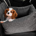 A small brown and white puppy looks over the edge of the Paw PupProtector™ Memory Foam Dog Car Bed - Single Seat in a car