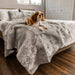 A small dog is pictured sitting on a bed adorned with the Paw PupProtector™ Short Fur Waterproof Throw Blanket - Grey