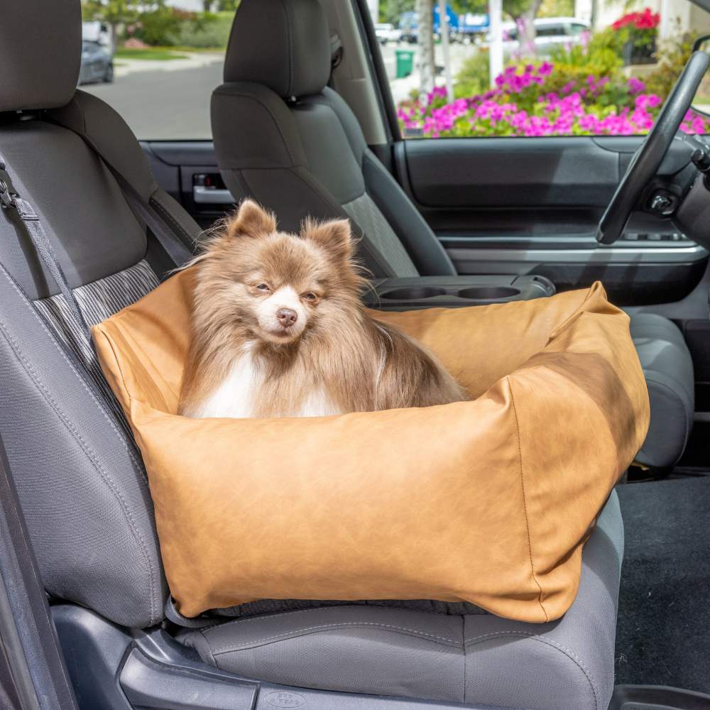 A small dog is sitting in the front passenger seat of a car in the Paw PupProtector™ Faux Leather Memory Foam Dog Car Bed - Camel Single Seat Dog Bed