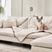 A small dog is sitting on a couch covered with the Paw PupProtector™ Short Fur Waterproof Throw Blanket - Polar White in a cozy living room