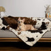 A small dog lounges on a sofa with the Paw PupProtector™ Waterproof Throw Blanket - Brown Faux Cowhide Dog Blankets For Couch