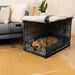 A small dog rests comfortably inside a black wire crate lined with soft grey padding, showcasing the Paw Upgrade Your Dog Crate Kit - Charcoal Grey