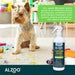 A small dog sitting on a carpet surrounded by a mess, with the ALZOO Enzyme-Based Stain & Odor Remover Spray 16oz - Apple Blossom bottle