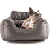 A small grey and white dog is lying in a Paw PupProtector™ Memory Foam Dog Car Bed - Single Seat, looking to the side