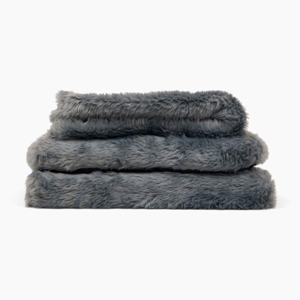 A stack of three grey, furry blankets from the Paw Upgrade Your Dog Crate Kit - Charcoal Grey