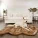 A white dog lounging on a Curve Sable Tan Paw PupRug Faux Fur Orthopedic Dog Bed in a bright, minimalist living room