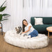 A woman and her dog share a joyful moment on the White with Brown Accents Paw PupCloud™ Human-Size Faux Fur Memory Foam Dog Bed