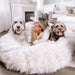 A woman and two dogs lie happily on the White with Brown Accents Paw PupCloud™ Human-Size Faux Fur Memory Foam Dog Bed in a stylish, cozy home setting