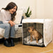 A woman happily interacts with a dog sitting inside a black wire crate lined with white padding from the Paw Upgrade Your Dog Crate Kit - Polar White